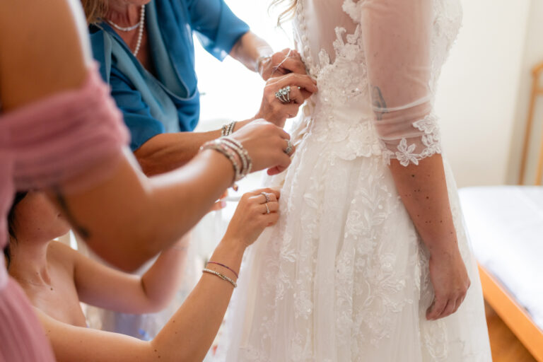 Particolare mani che allacciano il vestito da sposa